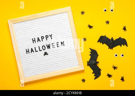 Tableau en feutre avec texte, citation, batte noire, araignées sur fond jaune vue du dessus Flat Lay Happy Halloween Creative concept carte de vacances bannière Banque D'Images