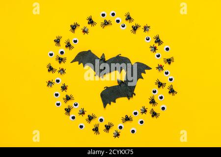 Cadre rond d'araignées et de mouches noires, yeux et chauve-souris à l'intérieur sur fond jaune vue du dessus Flat Lay Happy Halloween Creative concept Holiday Banque D'Images