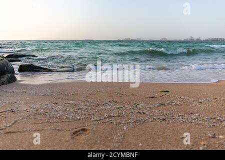 Vagues s'écrasant sur la rive du golfe Persique, paysage marin vu de l'île de Dubai Bluewaters, côte de Dubaï en arrière-plan, plage de sable. Banque D'Images