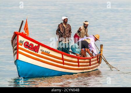 Les pêcheurs qui se mettent à chercher du filet sur leur bateau de pêche sur l'océan arabe au large de la populaire plage de Marari; Mararikulam, Alappuzha (Alleppey), Kerala, Inde Banque D'Images