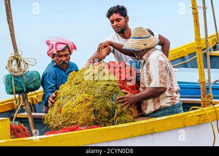 Pêcheurs qui rassemblent des filets sur leur bateau de pêche pour apporter à la rive à la plage populaire de Marari; Mararikulam, Alappuzha (Alleppey), Kerala, Inde Banque D'Images