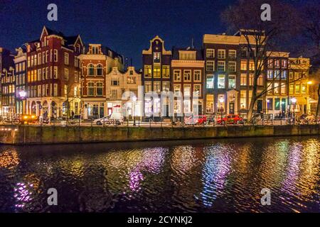 Vue de la nuit de bâtiments le long d'un canal à Amsterdam, avec des reflets dans l'eau Banque D'Images