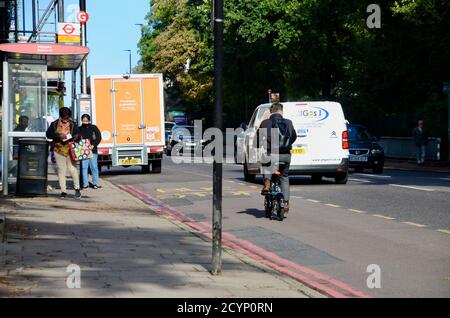 un homme fait un vélo électrique sur la route de l'arcade highgate londres, Royaume-Uni Banque D'Images