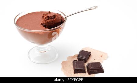 Bol transparent avec mousse au chocolat et cuillère à café et trois morceaux de chocolat noir isolé sur fond blanc Banque D'Images