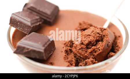 Bol transparent avec mousse au chocolat et cuillère à café et trois morceaux de chocolat noir isolé sur un fond blanc gros plan Banque D'Images