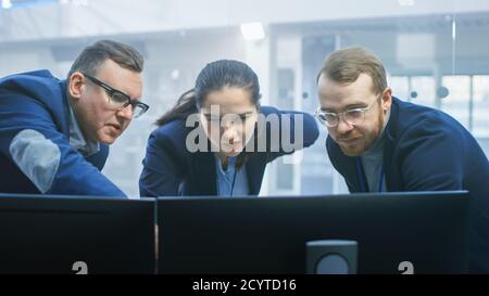 Les ingénieurs de conception automobile travaillent et discutent de quelque chose sur un écran d'ordinateur à côté d'un prototype de châssis de voiture électrique. En haute technologie Banque D'Images