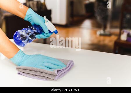 Main avec la table de nettoyage des gants avec un spray désinfectant et une serviette COVID-19. Banque D'Images