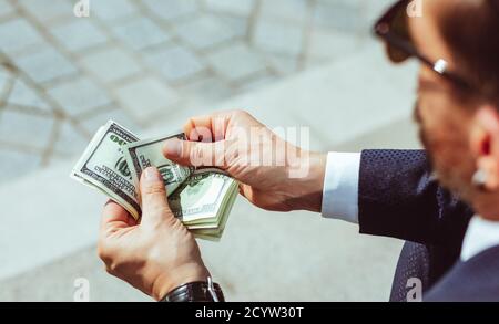 Homme d'affaires en costume tient une wad d'argent entre ses mains. L'homme réussi compte les factures. Photo de haute qualité Banque D'Images