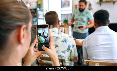 Femme prenant des photos avec mobile dans un atelier de cuisine Banque D'Images