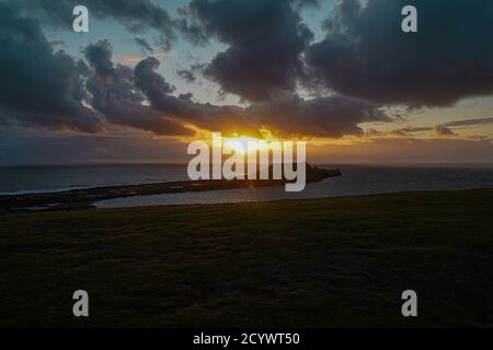 Coucher de soleil sur Gower Peninsular Rhossilli Bay Worm Rock formation rouge ciel Banque D'Images