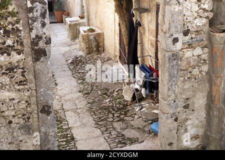 Vieux lavabos en pierre et lavage pendant à sécher sur la petite rue pavée d'Erice, Sicile Banque D'Images