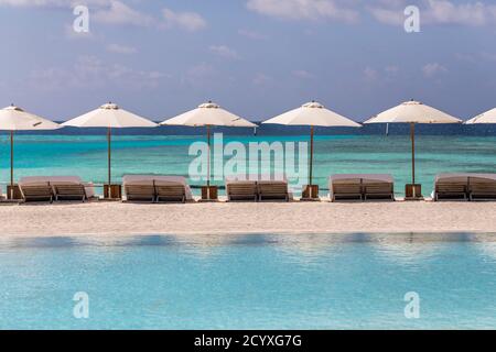 Como Maalifushi; chaises longues et parasols; Maldives Banque D'Images