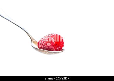 Le fruit mûr de framboise se trouve dans une cuillère d'argent sur un arrière-plan blanc Banque D'Images