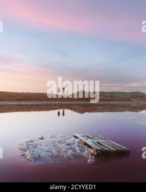 Cristaux de sel dans l'eau rose lac de sel en Ukraine, Europe. Deux photographes en arrière-plan. Photographie de paysage Banque D'Images