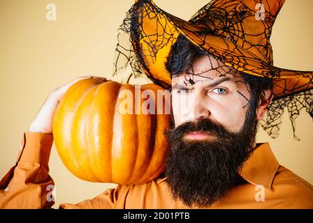 Ingrédients de cuisine de saison de Thanksgiving. Beau homme en chapeau d'Halloween tenant la citrouille - portrait gros plan. Jeune homme avec chapeau de sorcière prêt à Banque D'Images