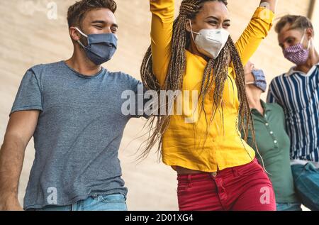 De jeunes amis dansant ensemble tout en portant un masque facial extérieur - Des gens heureux s'amuser en ville après la quarantaine du virus corona Banque D'Images