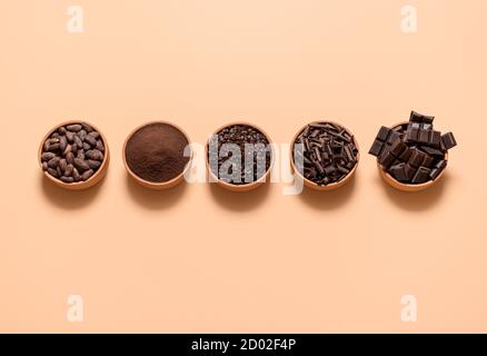 Ingrédients de chocolat, fèves de cacao, poudre de cacao, morceaux de chocolat dans des bols, isolés sur fond beige. Plat avec cacao et chocolat noir. Banque D'Images