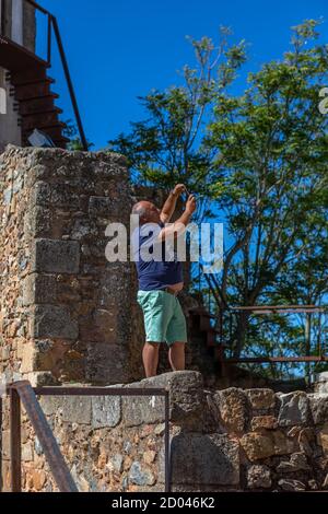 Figueira de Castelo Rodrigo, Portugal - 08 23 2020: Vue d'un touriste senior prenant une photo avec son téléphone, sur le village intérieur de la forteresse médiévale Banque D'Images