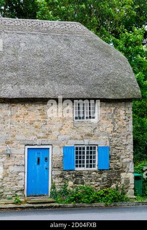 West Lulworth, Royaume-Uni - 19 juillet 2020: Belle maison de campagne en chaume avec porte et volets bleu cobalt, couleur Dorset unique Banque D'Images