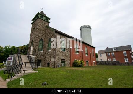 Une petite église Cobblestone avec une tour d'eau derrière elle En banlieue de Pennsylvanie Banque D'Images