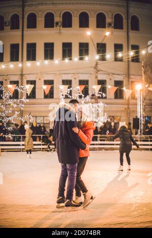 Beautiful couple ont in ice arena. date active du patin à glace sur la patinoire en soirée place de la ville en hiver la veille de Noël. À la Saint-Valentin Banque D'Images