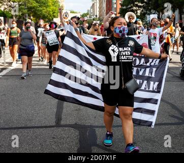 Une femme dans un t-shirt Black Lives Matter porte un drapeau BLM en route vers la marche sur Washington, 57 ans après MLK, Washington, DC, Etats-Unis Banque D'Images