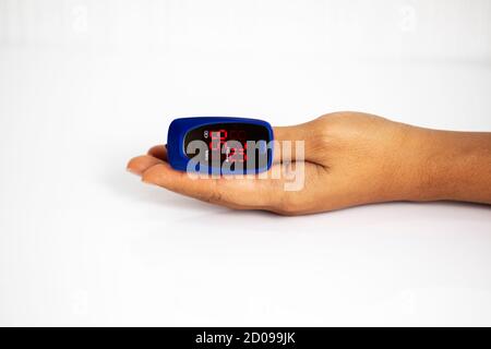 Oxymètre de pouls sur le doigt utilisé pour tester le niveau d'oxygène dans le sang en cas d'infection virale des poumons avec la femme main reposant sur un fond blanc Banque D'Images