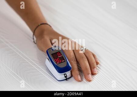 Oxymètre de pouls sur un doigt de femme utilisé pour tester le sang niveau d'oxygène en cas d'infection virale des poumons avec la main de la femme se reposant Banque D'Images
