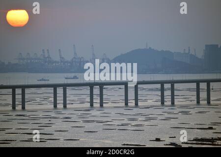 Pont de la baie de Shenzhen traversant Deep Bay, entre Hong Kong et Shenzhen, en Chine, au coucher du soleil avec les terminaux à conteneurs Shekou en arrière-plan Banque D'Images