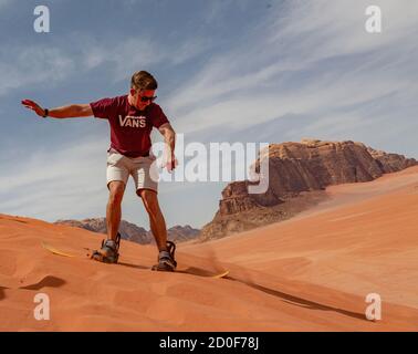 Wadi Rum, JORDANIE - 2019-04-23 - l'Homme tente d'utiliser une planche de descendre une dune de sable. Banque D'Images