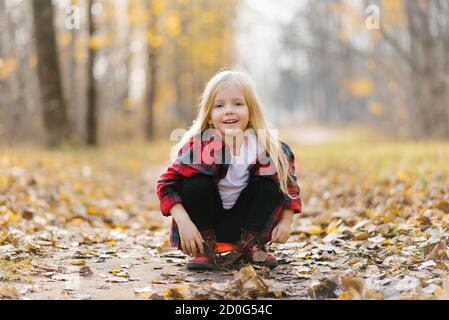 Une petite fille dans le parc. Jour d'automne ensoleillé dans le parc de la ville. Orange-jaune calme humeur. Bonne enfance Banque D'Images