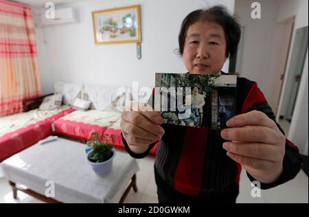 Lin Qinqguo, a resident of one of the apartment buildings where the local government built homes for former miners and farmers as part of an urbanisation programme, shows a picture taken with her mother at her old house, during an interview with Reuters in Mentougou district, in a suburb of Beijing, February 28, 2013. China plans major bond market reform to raise the money the ruling Communist Party needs for a 40 trillion yuan ($6.4 trillion) urbanisation programme to buoy economic growth and close a chasm between the country's urban rich and rural poor. REUTERS/Kim Kyung-Hoon (CHINA - Tags: 