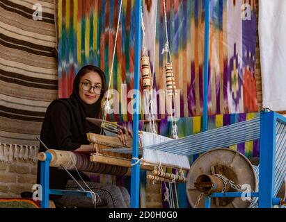 Isfahan, Iran - 2019-04-12 - Femme tisse sur un métier à main en tissu. Banque D'Images