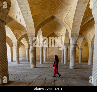 Shiraz, Iran - 2019-04-08 - Femme promenades par colonnes cannelées de mosquée Vakil. Banque D'Images