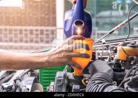 Auto mécanicien est le remplissage de l'huile moteur de la voiture à l'intérieur du centre de réparation automobile, l'industrie automobile et les idées de garage. Banque D'Images