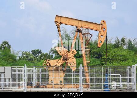 Ancien vérin de pompe à huile rouillée, extraction de pétrole brut et naturel gaz provenant de puits sur fond vert Banque D'Images