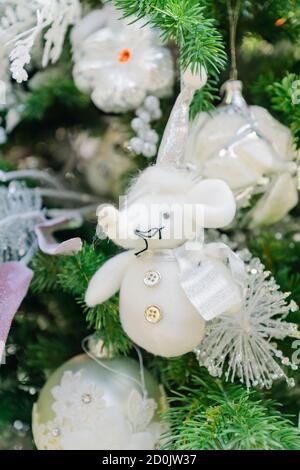 Symbole de l'année 2020. Rat jouet blanc dans un chapeau de noël suspendu sur un arbre en fourrure enneigé. Décoration intérieure festive. Banque D'Images