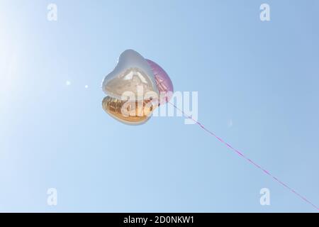Ballons en forme de cœur volant dans le ciel attaché à une corde Banque D'Images