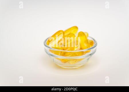 Supplément d'huile de poisson, concept médical et de santé, capsules de gel doux dans un bol en verre sur fond blanc Banque D'Images