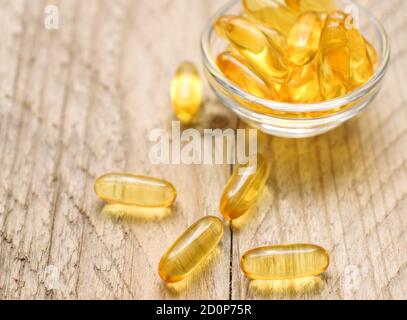 capsules d'huile de foie de poisson omega 3 dans un petit bol en verre. Gros plan de pilules dorées translucides. Supplément nutritionnel en acides gras sains. Banque D'Images