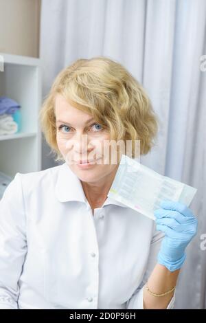 femme d'âge moyen en manteau blanc contenant des aiguilles pour seringues. Médecin femme, professionnel de la santé Banque D'Images