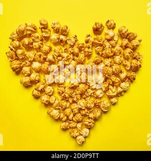 Pop-corn caramel en forme de coeur sur fond jaune. J'adore le pop-corn. Mets sucrés Banque D'Images