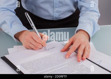 Une femme d'affaires signe des documents en gros plan. Banque D'Images