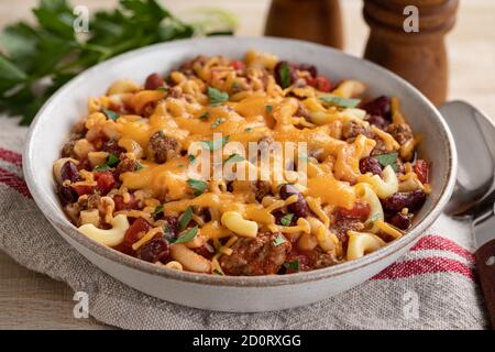 Gros plan du bol de macaroni au Chili avec du fromage cheddar fondu sur une table en bois Banque D'Images