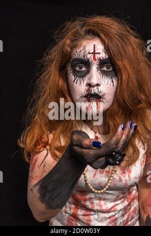 Une tête rouge avec maquillage noir blanc, portant des vêtements blancs sanglants. Concept Halloween Banque D'Images