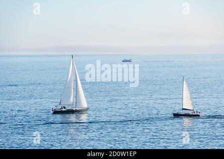 Deux voiliers et un ferry entrent et partent de la Ria de Pontevedra en Galice au crépuscule. Banque D'Images