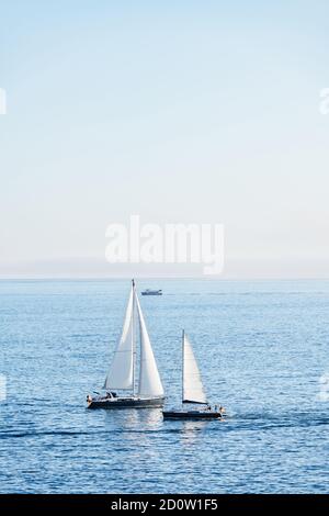 Deux voiliers et un ferry entrent et partent de la Ria de Pontevedra en Galice au crépuscule. Banque D'Images