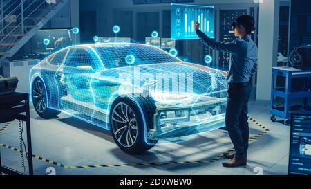 Ingénieur automobile utilisant le casque de réalité virtuelle pour l'analyse et l'amélioration de la conception de modèles 3D de voiture électrique virtuelle. La visualisation graphique 3D s'affiche Banque D'Images
