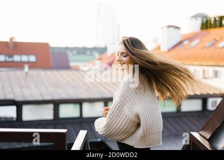 Une belle jeune brunette sourit largement, ses cheveux se développant dans le vent comme elle tourne autour. Portrait d'un joli modèle féminin dans un style tendance Banque D'Images