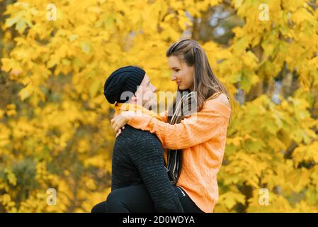 Un couple amoureux s'embrasse dans la forêt d'automne. Un jeune homme et une fille marchent, un gars tient une fille dans ses bras. Voyagez en mode automobile Banque D'Images